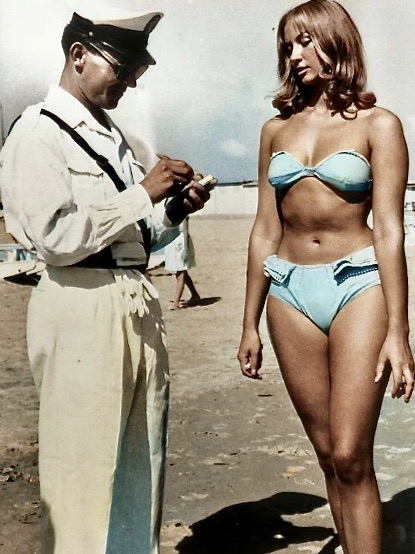 A police officer issuing a woman a ticket for wearing a bikini on a beach Italy - 1957