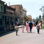Disneyland, 1956. A well-dressed family head toward the Golden Horseshoe Revue and the Rivers of America beyond.